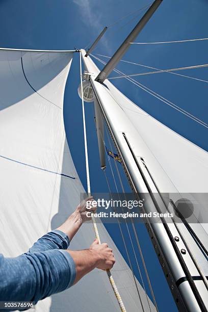 man pulling ropes on yacht - albero maestro foto e immagini stock