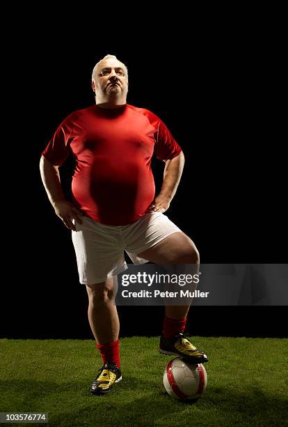 large sportsman with foot on football - chubby men stock-fotos und bilder