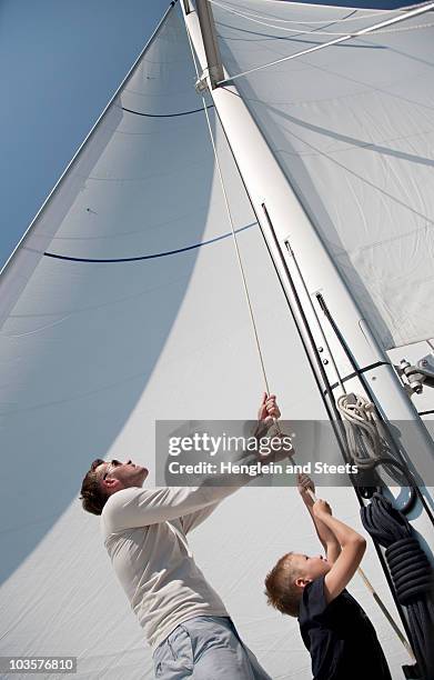 father and son pulling rope on yacht - father son sailing stock pictures, royalty-free photos & images