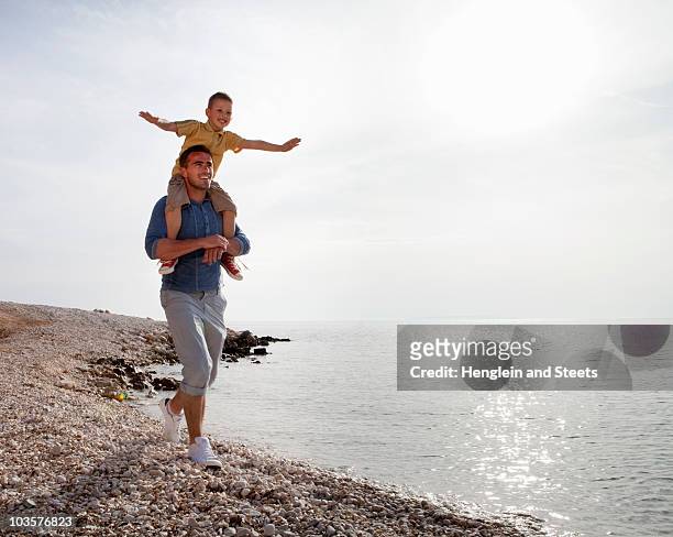 father and son at the beach - mann mit kind auf den schultern stock-fotos und bilder