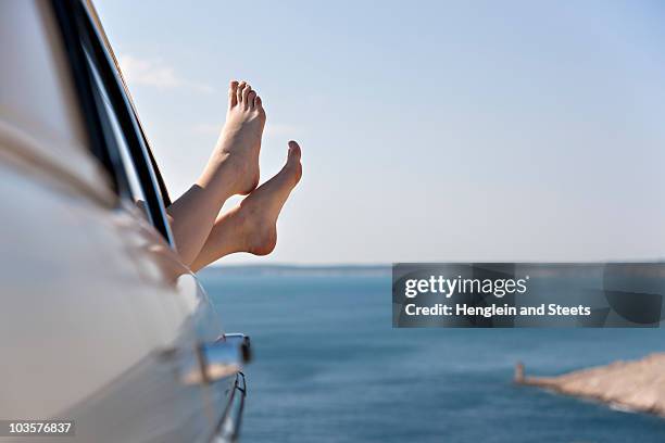 woman stretching feet from car by sea - womens beautiful feet 個照片及圖片檔