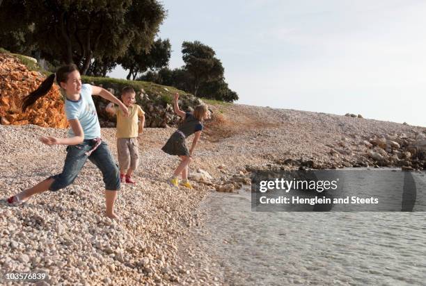 children at the beach - skimming stones stock-fotos und bilder