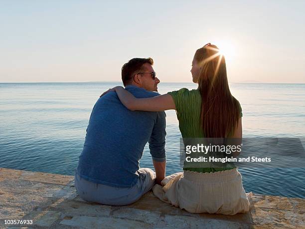 couple by sea watching sun set - sun flare couple stock-fotos und bilder