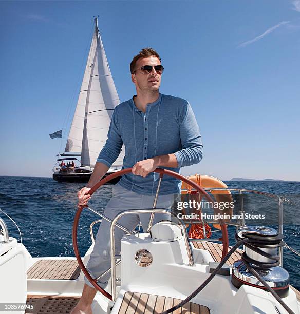 man steering yacht - yachting stock pictures, royalty-free photos & images