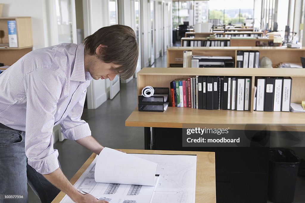 Man studying blueprint in office