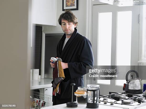 man standing in kitchen, empting dishwasher - robe stock pictures, royalty-free photos & images