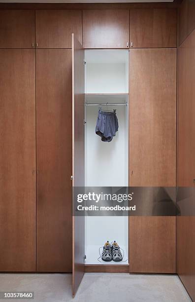 athletic shoes and running shorts in locker with open door - open workouts stock-fotos und bilder