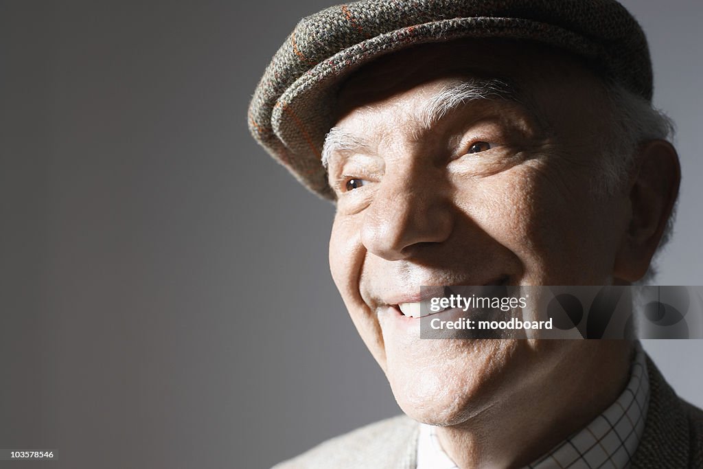 Senior man in flat cap, close up, in studio