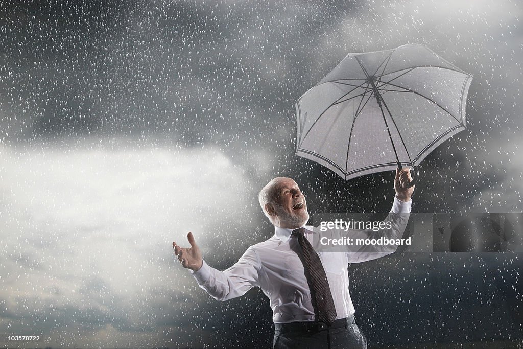 Businessman holding umbrella, Laughing in Storm, low angle view