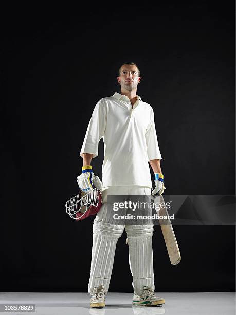 cricket player, standing holding cricket bat, low angle view - shin guard stock-fotos und bilder