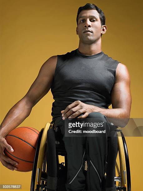 Paraplegic athlete sitting in wheelchair holding basketball