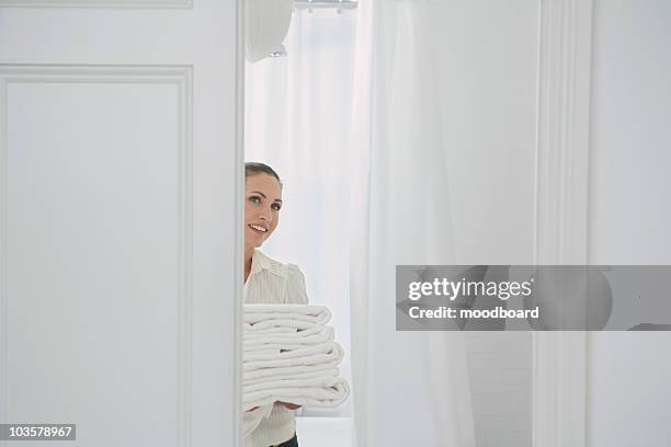 woman carrying folded linen in home - folded towel stock-fotos und bilder