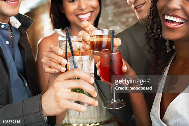 friends toasting  in bar, close up on glasses - 4 cocktails stockfoto's en -beelden