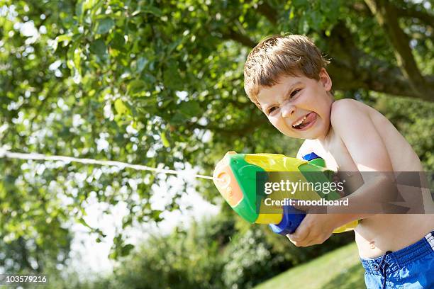 boy in park shooting pump action water pistol - toy gun stock pictures, royalty-free photos & images