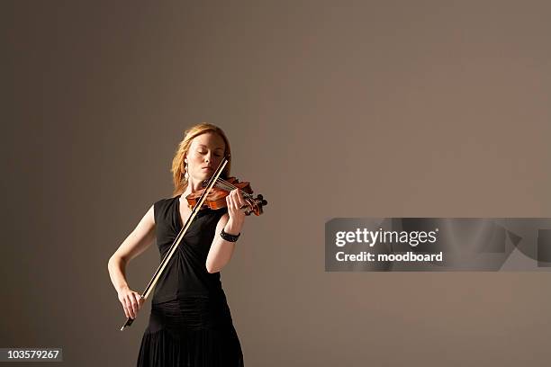 woman playing violin - strijkstok stockfoto's en -beelden