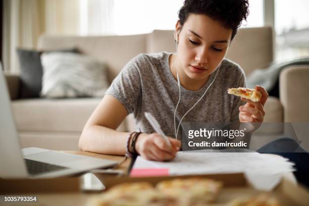 vrouwelijke student studeren en luisteren naar muziek thuis - woman junk food eating stockfoto's en -beelden