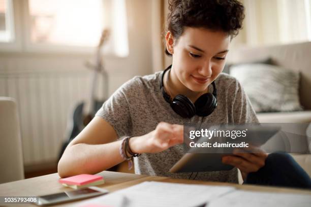 smiling young woman using digital tablet at home - choosing imagens e fotografias de stock