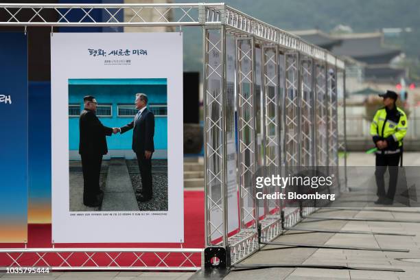 Police officer walks past a photo exhibition featuring North Korean Leader Kim Jong Un and South Korean President Moon Jae-in at Gwanghwamun Square...