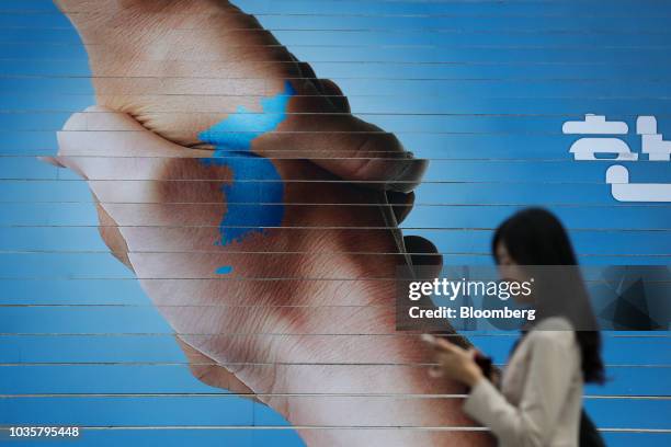 Woman walks past an advertisement depicting the Korean Peninsula to promote the inter-Korean summit in Seoul, South Korea, on Wednesday, Sept. 19,...
