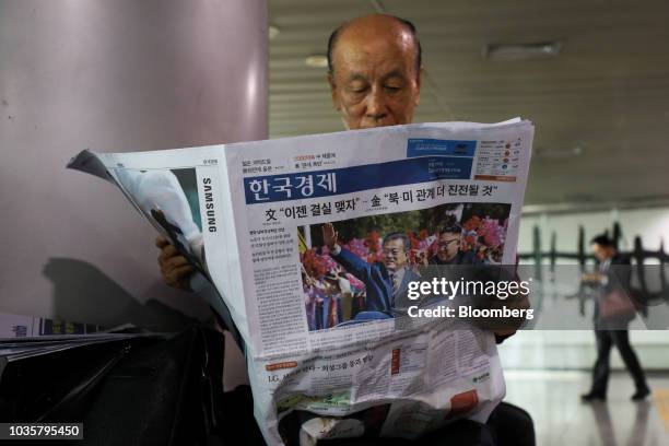 Man reads a newspaper featuring a photograph of North Korean Leader Kim Jong Un and South Korean President Moon Jae-in on the front page at Seoul...