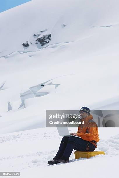 hiker using laptop on snowy mountain peak - laptop high up stock pictures, royalty-free photos & images