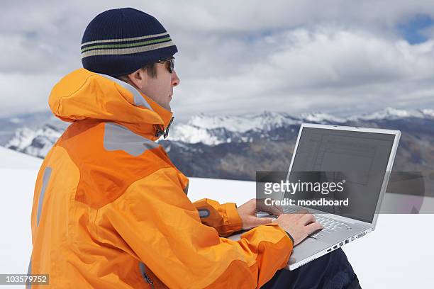 hiker using laptop on snowy mountain peak - mac laptop stock pictures, royalty-free photos & images