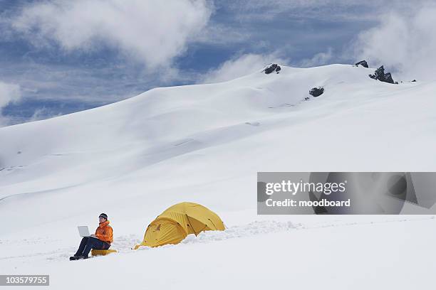 hiker using laptop outside of tent on snowy mountain peak - laptop high up stock pictures, royalty-free photos & images