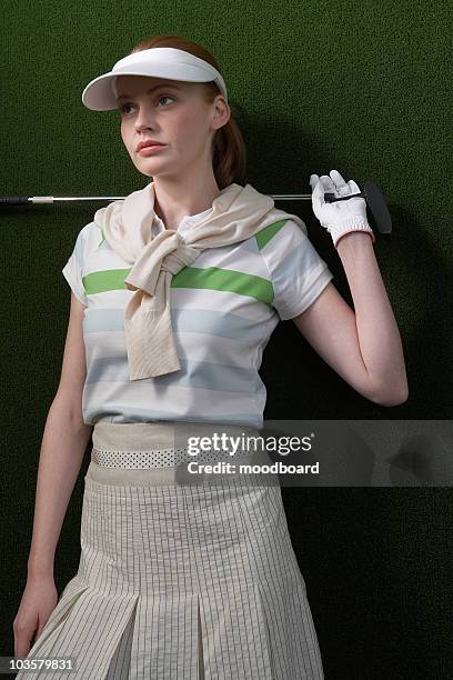 woman in visor holding golf club behind shoulders, portrait - mid adult woman sweater stock pictures, royalty-free photos & images