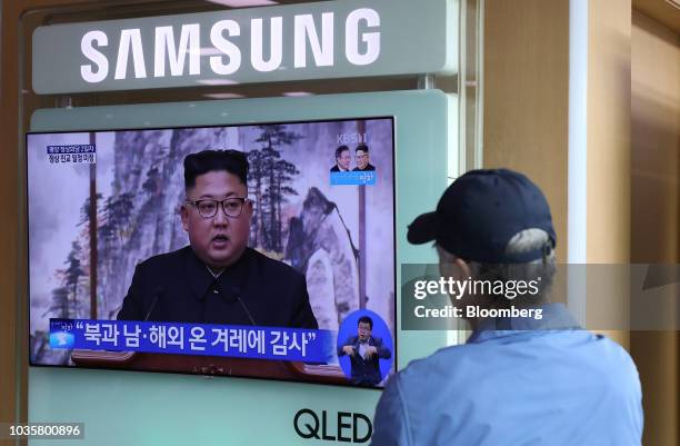 Man watches a television screen showing a broadcast, featuring North Korean leader Kim Jong-un attending a news conference with South Korean...