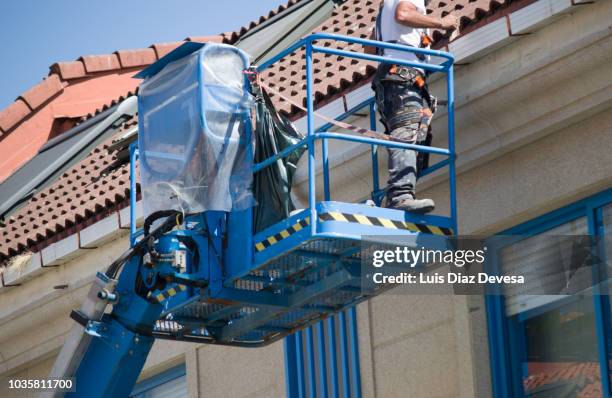 cleaning guttering of a building with hydraulic crane - dakgoot stockfoto's en -beelden
