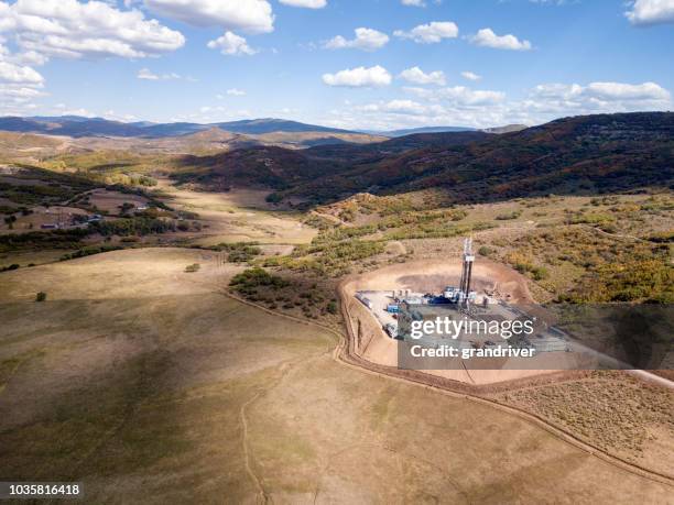 aerial view of a fracking drilling rig in the autumn mountains of colorado - oil rig stock pictures, royalty-free photos & images