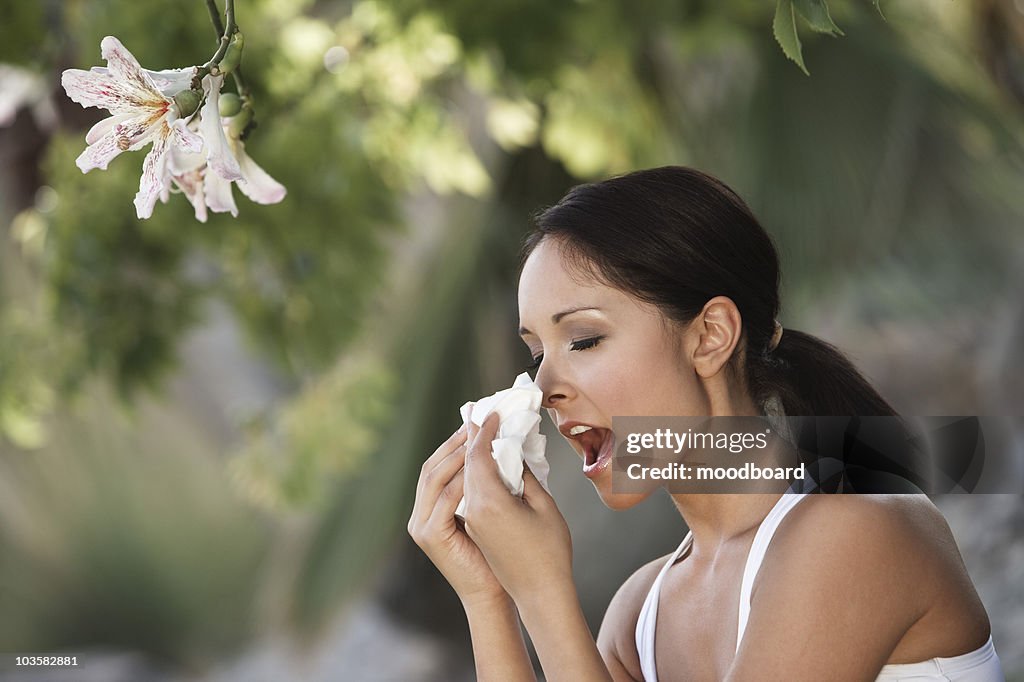 Woman sneezing under tree