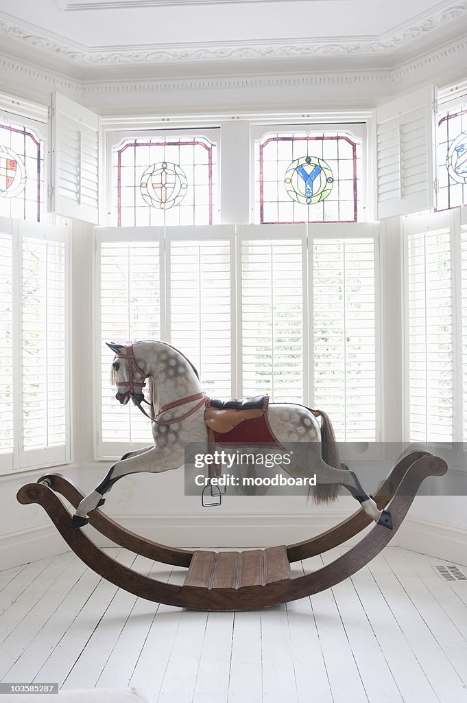 Antique rocking horse in bay window with stained glass,  London
