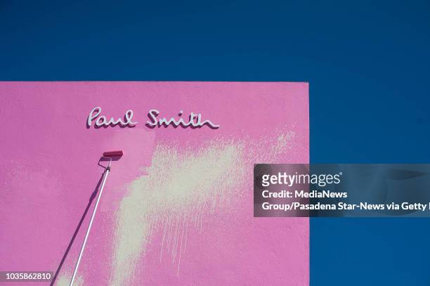 Painters finish covering up graffiti that read "Go F... Ur Selfie" on the bright pink wall of British fashion designer Paul Smith's flagship store on...