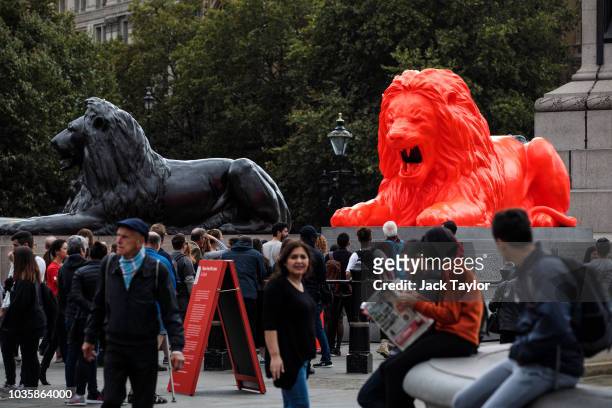 An installation featuring a bright red lion titled 'Please Feed The Lions' by British designer Es Devlin sits at the base of Nelson's Column beside...