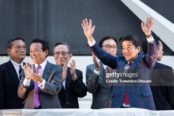 Japan's Prime Minister Shinzo Abe waves as Deputy Prime Minister and Finance Minister Taro Aso claps during a campaign rally for the Liberal...