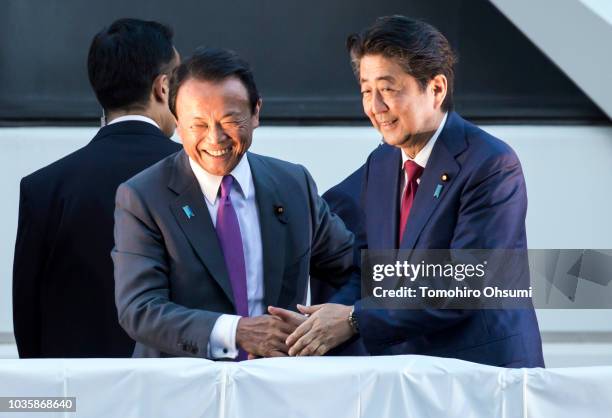 Japan's Prime Minister Shinzo Abe shakes hands with Deputy Prime Minister and Finance Minister Taro Aso during a campaign rally for the Liberal...