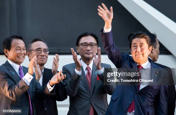 Japan's Prime Minister Shinzo Abe waves as Deputy Prime Minister and Finance Minister Taro Aso claps during a campaign rally for the Liberal...