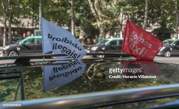 Banners stating "Somos Taxi!" and "Proibido a Ilegales" flute on top of a taxi cab parked at Avenida da Liberdade on September 19, 2018 in Lisbon,...