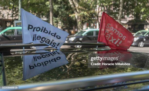 Banners stating "Somos Taxi!" and "Proibido a Ilegales" flute on top of a taxi cab parked at Avenida da Liberdade on September 19, 2018 in Lisbon,...