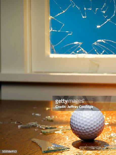golf ball and broken window - ball on a table stockfoto's en -beelden