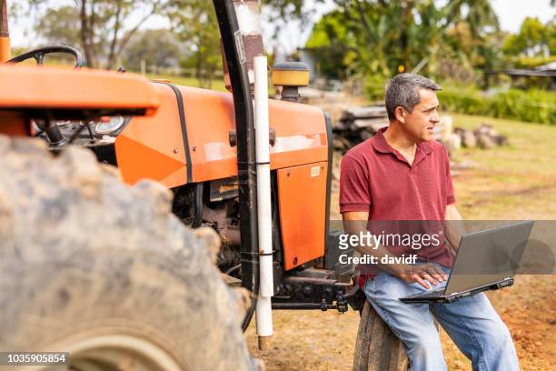 midden leeftijd man met behulp van een laptopcomputer op zijn boerderij - australian farmer stockfoto's en -beelden