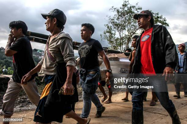 Workers carry a coffin of a victim killed by a landslide on September 19, 2018 in Itogon, Benguet province, Philippines. Dozens of people are feared...