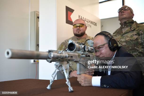 Russian President Vladimir Putin looks through the scope as he shoots a Chukavin sniper rifle during a visit to the military Patriot Park in Kubinka,...