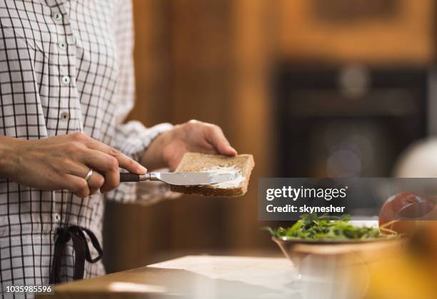 mujer irreconocible separarse mantequilla en su pan tostado en la mañana. - untar de mantequilla fotografías e imágenes de stock