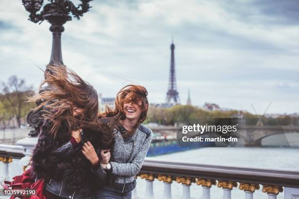 glückliche freunde in paris mit zerzausten haaren an windigen tag - hair flying stock-fotos und bilder