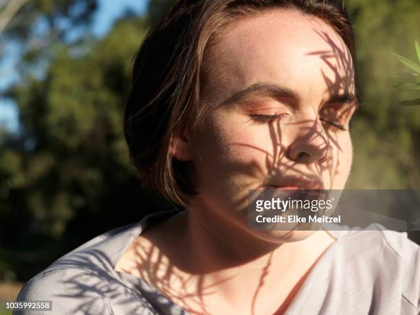 young woman enjoying the sunshine on her face - perception stock-fotos und bilder
