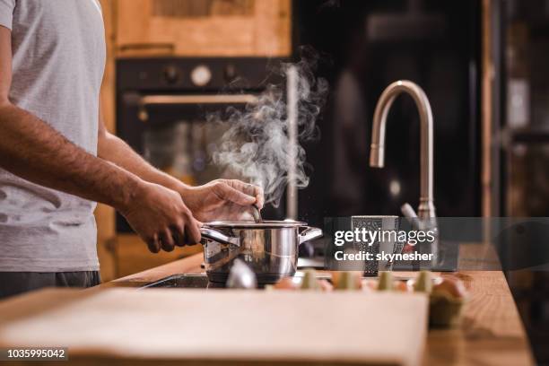 unrecognizable man stirring soup in a saucepan while making lunch in the kitchen. - boiling steam stock pictures, royalty-free photos & images