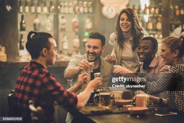 cheerful friends having fun while toasting with shots during their night out in a bar. - tequila shot stock pictures, royalty-free photos & images