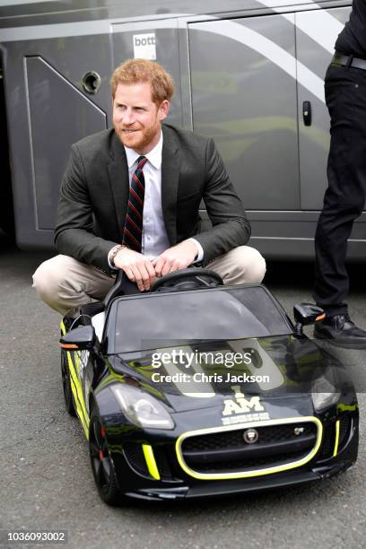 Prince Harry, Duke of Sussex sits in a mini car as he talks with members of The Invictus Games Foundation GT Championship team during a visit to The...